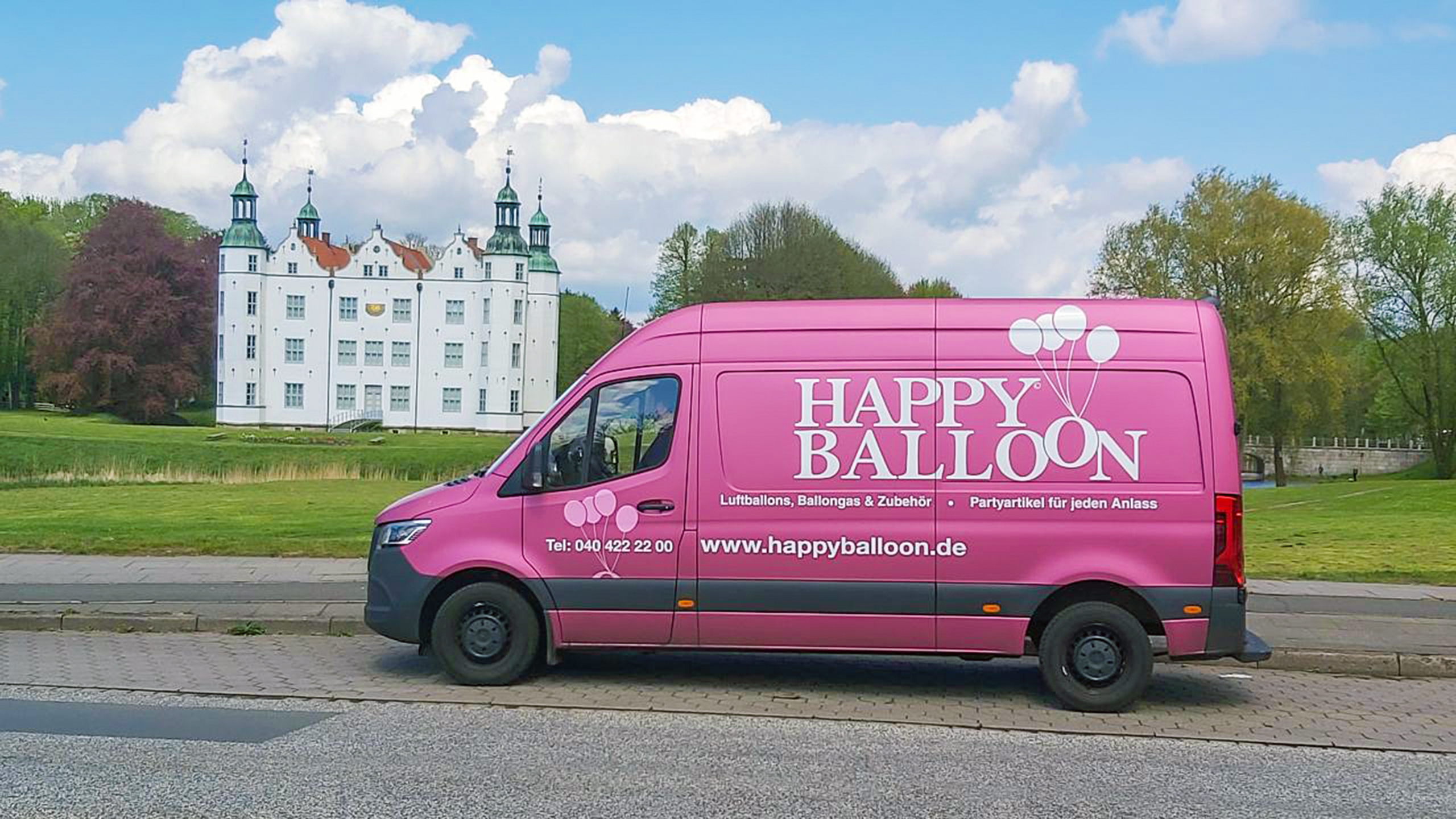 Pinker Happy-Balloon-Transporter vor einem Schloss